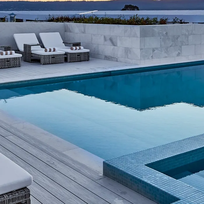 A rooftop pool and sun lounges at dusk